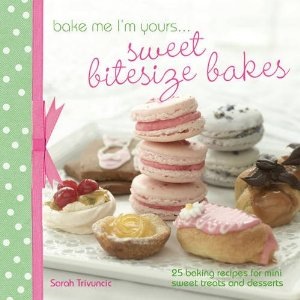 Cover of "Bake Me I'm Yours... Sweet Bitesize Bakes" by Sarah Trivuncic; image shows a selection of small cakes and patisserie. The book has a green polka dot spine edged with pink ribbon and a bow.